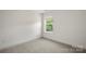 Empty bedroom with neutral carpet, white walls, and a bright window offering natural light at 443 Faith Sw Dr, Concord, NC 28027