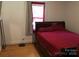 Bedroom with red bedspread and curtains, featuring hardwood floors and a window at 448 Belk St, Lancaster, SC 29720
