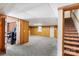 Basement featuring carpet, wood panel walls, drop ceiling, and stair access to the floor above at 5563 Grace Chapel Rd, Hickory, NC 28601