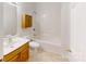 Bright bathroom features a shower-tub combo and a wooden cabinet above the toilet at 6825 Woodleaf Rd, Woodleaf, NC 27054