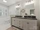 Bathroom with a dual sink vanity, black countertop, decorative mirrors and fixtures, and tiled floor at 6934 Loretta Pl, Charlotte, NC 28215