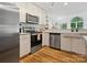 Well-lit kitchen with stainless steel appliances, white cabinets, and a farmhouse sink at 6934 Loretta Pl, Charlotte, NC 28215