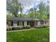 Charming brick home with a well-manicured lawn and blooming white azaleas along the front at 7026 Tabor Ln, Charlotte, NC 28211