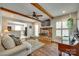 Cozy living room with a brick fireplace, exposed wooden beams, and a view to the kitchen at 7026 Tabor Ln, Charlotte, NC 28211