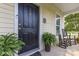 Inviting front porch with a black door, rocking chairs, and potted ferns, exuding cozy charm at 7344 Gilead Rd, Huntersville, NC 28078