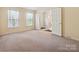 Spacious bedroom showcasing double doors, neutral carpet, and bright windows adorned with sheer curtains at 7639 Winterset Dr, Charlotte, NC 28270