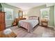 Calming bedroom with light green walls and hardwood floors features a full bed and natural light at 7639 Winterset Dr, Charlotte, NC 28270