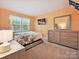 Bedroom showcasing a floral bed set, wooden dresser and window overlooking nature at 7639 Winterset Dr, Charlotte, NC 28270