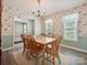 Charming dining room featuring wood flooring, floral wallpaper, and a classic wooden table set for a meal at 7639 Winterset Dr, Charlotte, NC 28270
