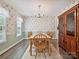 Cozy dining room with wooden table and chairs, complemented by floral wallpaper, chair rail and stylish chandelier at 7639 Winterset Dr, Charlotte, NC 28270
