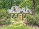 Charming green home with dormer windows and a vibrant orange front door, set amidst lush landscaping and mature trees at 7639 Winterset Dr, Charlotte, NC 28270