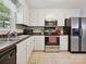 Corner view showcasing a well-equipped kitchen with stainless steel appliances, black countertops, and ample cabinet space at 7639 Winterset Dr, Charlotte, NC 28270