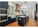 Modern kitchen featuring navy cabinets, a large island, stainless appliances, and a custom range hood at 7903 Tottenham Ct, Waxhaw, NC 28173