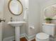 Stylish powder room featuring pedestal sink, decorative mirror, and modern fixtures at 7903 Tottenham Ct, Waxhaw, NC 28173