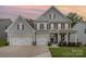 Beautiful two-story home featuring gray siding, black shutters, a three-car garage, and well-maintained landscaping at 808 Dogwood Creek Ln, Indian Trail, NC 28079