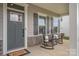 Inviting front porch with gray door, gray shutters, and classic black rocking chairs for relaxed outdoor living at 808 Dogwood Creek Ln, Indian Trail, NC 28079