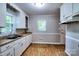 Bright kitchen featuring wood-look flooring, white cabinets, and ample natural light from two windows at 828 Williams St, Gastonia, NC 28052