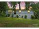 Twilight view of updated single story home in the evening, complemented by mature trees at 10514 Harbor Dr, Charlotte, NC 28214