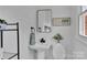Well-lit bathroom featuring a pedestal sink, decorative mirror, and charming floral accents at 113 Lou Dr, Gastonia, NC 28052