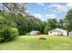 A home's backyard is shown with a fire pit, mature trees, and two garages at 1145 Earl Rd, Shelby, NC 28152