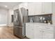 Modern kitchen boasts stainless steel refrigerator and white cabinets with subway tile backsplash at 125 White Apple Way, Statesville, NC 28625