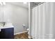 Bathroom boasts single vanity with storage, wood-look flooring and white shower curtain at 12522 Palomino Dr, Midland, NC 28107
