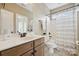 Bathroom features a wood vanity, a shower with curtain, neutral paint and tile flooring creating a modern look at 12525 Druids Glen Dr, Pineville, NC 28134