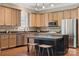Well-lit kitchen with wood cabinets, granite countertops, stainless steel appliances, and a center island with bar stool seating at 12525 Druids Glen Dr, Pineville, NC 28134