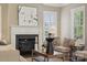 Living room featuring a fireplace, accent chair, and bright natural light from the shuttered windows at 12525 Druids Glen Dr, Pineville, NC 28134