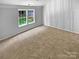 Bright bedroom featuring plush carpet, vertical trim accent wall, and a window overlooking the yard at 2010 Kansas City Dr, Monroe, NC 28110