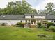 Backyard view of house with wooden deck, lush green lawn, and mature trees at 2032 Greenbrook Pkwy, Matthews, NC 28104