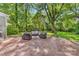 Backyard patio with brick pavers, outdoor seating, and a lush green lawn surrounded by mature trees at 2034 Lanier Ave, Charlotte, NC 28205