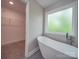 Sunlit bathroom with a modern soaking tub, large window, and a door to the walk-in closet at 292 Manchester Rd, Mount Gilead, NC 27306