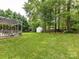 Expansive backyard featuring a pergola, green lawn, storage shed, swing, and perimeter landscaping at 3533 Weddington Ridge Ln, Matthews, NC 28105