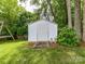 White storage shed surrounded by lush greenery and mature trees in a well-maintained backyard at 3533 Weddington Ridge Ln, Matthews, NC 28105