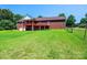 Expansive backyard view of a brick home featuring a wooden deck, lush green lawn, and partial fencing at 4010 Carlton Dr, Claremont, NC 28610