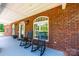 Inviting front porch with rocking chairs, brick facade, arched windows, and decorative exterior lighting at 4010 Carlton Dr, Claremont, NC 28610
