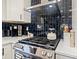 Modern kitchen featuring stainless steel range, white cabinets, black backsplash, and quartz countertops at 4101 Tipperary Pl, Charlotte, NC 28215