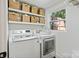 Bright laundry room featuring white appliances, woven baskets, and a window offering natural light at 4101 Tipperary Pl, Charlotte, NC 28215