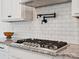 Close-up of a gas stovetop, granite countertops, and white subway tile backsplash at 4535 Falls Lake Sw Dr, Concord, NC 28025