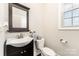 Powder room featuring a dark wood vanity, modern fixtures, and natural light from a window at 6029 Phyliss Ln, Mint Hill, NC 28227