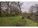A view of the spacious backyard with a wood fence and mature trees at 613 E Liberty St, Salisbury, NC 28144