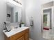 Half bath with wood vanity, white countertop, framed mirror, and a view to the back entryway at 713 Hickory Hill Ct, Gastonia, NC 28054