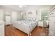 Bright bedroom with hardwood floors, a white bed frame with floral comforter, and natural light at 713 Hickory Hill Ct, Gastonia, NC 28054