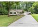 Charming home featuring a long driveway and a front yard surrounded by lush greenery and mature trees at 713 Hickory Hill Ct, Gastonia, NC 28054
