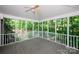 Screened in porch with wooded views, ceiling fan, and light-colored railings at 10408 Hadleigh Pl, Charlotte, NC 28210