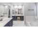 Spa bathroom with soaking tub, marble floors, double vanity, and vanity mirror and stool at 10418 Pullengreen Dr, Charlotte, NC 28277