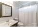 Clean and simple bathroom featuring a vanity, toilet, and shower with white curtain at 10418 Pullengreen Dr, Charlotte, NC 28277
