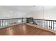 Bright loft area featuring hardwood floors, white walls, and black railing at 10418 Pullengreen Dr, Charlotte, NC 28277