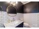 Chic powder room features modern gold fixtures, marble countertop, white subway tiles, and contrasting dark walls at 10418 Pullengreen Dr, Charlotte, NC 28277